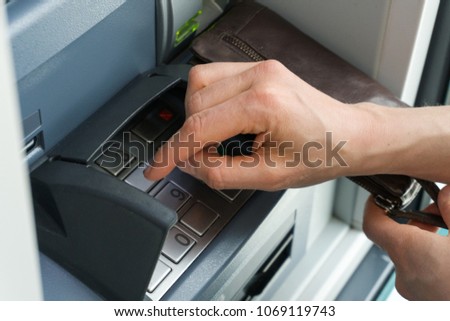 female hand entering PIN code at an ATM to get money