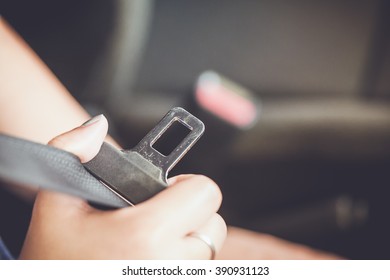 female hand fastening safety belt in car