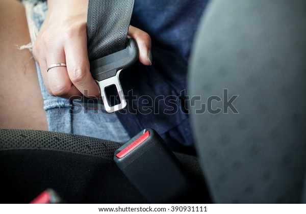 female hand fastening\
safety belt in car