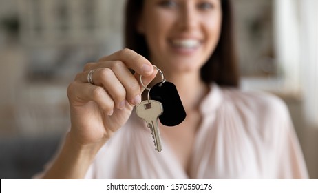 Female hand first time home owner renter customer holding house key, single woman buy real estate, mortgage loan investment, house property purchase ownership concept, close up view, focus on keyring