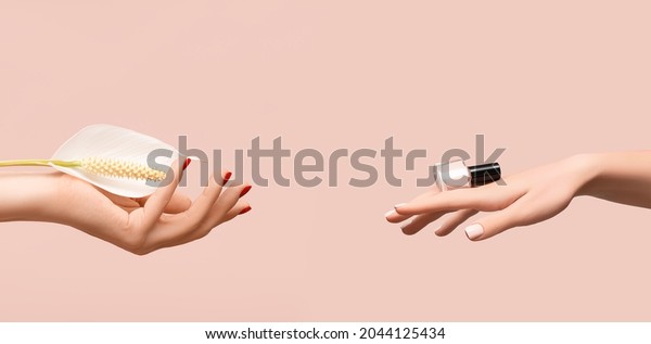 Female hand with glitter red nail design. Female\
hand hold white Spathiphyllum flower. Woman hand on pink\
background. Glitter red nail polish manicure. Female hand hold pink\
nail polish bottle.