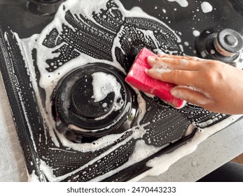 female hand in gloves with rag sponge a chemical foam cleaning gas stove at home kitchen. Washing the hob gas cooker - Powered by Shutterstock