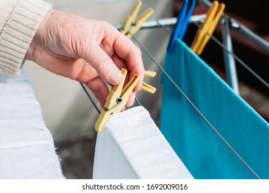 Female hand hanging freshly washed laundry on the wire - Shutterstock ID 1692009016