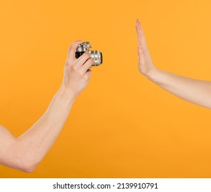 a female hand hides something from filming and camera yellow background close  up
