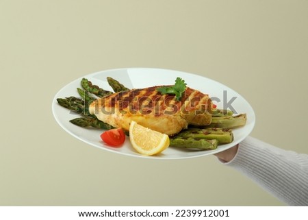 Female hand hold board with grilled chicken and asparagus