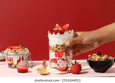 Female Hand Hold Drinking Jar with Strawberry Greek Yoghurt Parfait, Made eith Fresh Fruit, Yoghurt, and Granola. Concept Healthy Eating Diet Menu