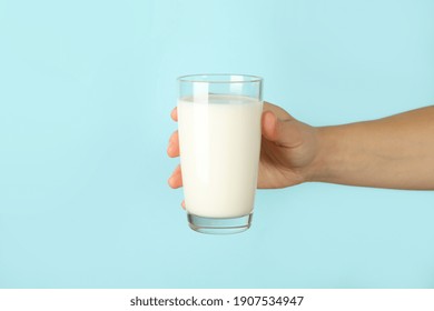 Female Hand Hold Glass Of Milk On Blue Background