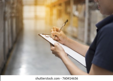 Female Hand Hold A Pen To Check Product In Warehouse For Import And Export The Shipping Cargo. Image With Lighting Flare Effect 