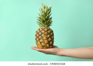 Female hand hold ripe pineapple on mint background - Powered by Shutterstock