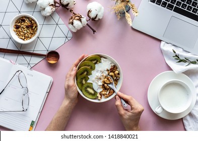 Female hand hold spoon over healthy breakfast concept bowl enjoy detox morning meal on work table background with laptop milk, woman eat natural granola nutrition detox food in home office, top view - Powered by Shutterstock