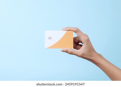 Female hand hold a white blank credit card for mockup. Modern way of banking and buying.