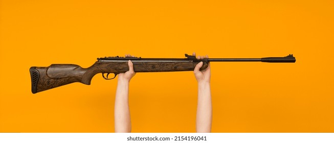 Female Hand Holding An Air Gun On A Colored Background