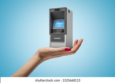 Female hand holding ATM machine on blue background. Banking and finance. Business success. Management and income.