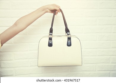 Female Hand Holding  Bag On White Brick Background