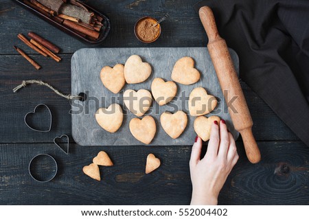 Female hand holding the baked cookies-hearts on the vintage wooden table