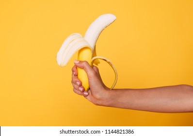 Female hand Holding Banana Fruit, Nutrition concept, human hand holding a banana isolated on orange background