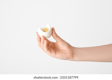 Female hand holding boiled chicken egg on white background - Powered by Shutterstock