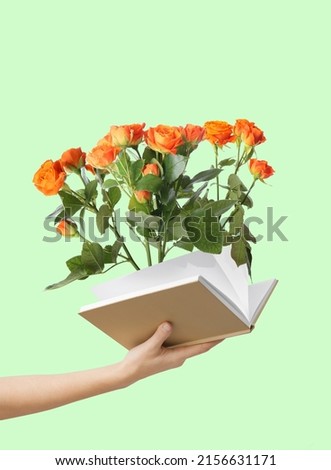 Female hand holding book with roses on green background