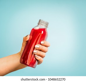 Female Hand Holding Bottle With Red Summer Drink: Smoothie Or Juice At Blue Background. 