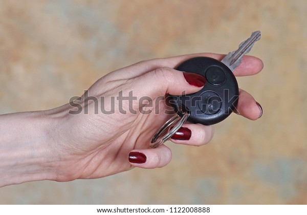 Female hand holding car key pressing remote\
control unlock button