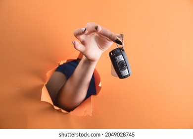 Female Hand Holding Car Keys On Orange Background