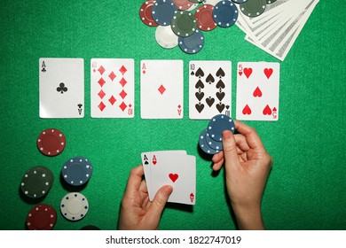 Female hand holding cards with poker chips and dollar banknotes on green table