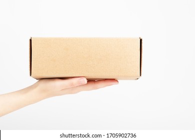 Female Hand Holding Carton Box. Food Conveyance. Fast Delivery Service. Mockup Style And Place For Text. Package And Shipping Concept. Isolated On White