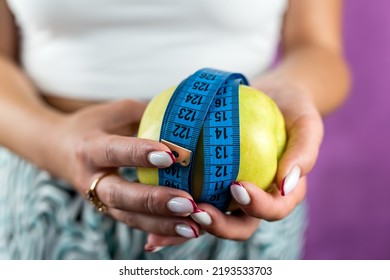 Female Hand Holding Centimeter Tape And Apple Fruit.Healthy Lifestyle Concept. Concept Of Natural Organic Food