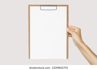 female hand holding clipboard with blank white sheet of paper isolated on gray background