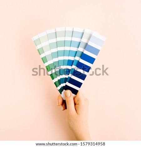 Female hand holding color swatches. Color trend palette. Flat lay, top view. 