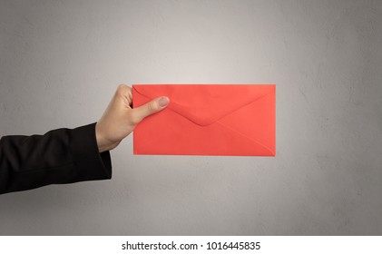 Female hand holding coloured and white envelope with empty wall background - Shutterstock ID 1016445835