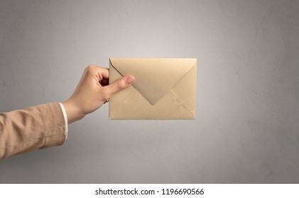 Female hand holding coloured and white envelope with empty wall background - Shutterstock ID 1196690566