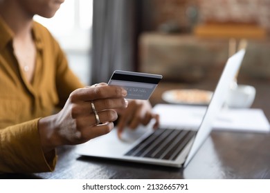 Female hand holding credit card at laptop close up. Young Black customer, shopaholic woman making payment for purchase on Internet, bank transactions, mortgage fees, buying on shop websites