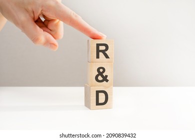 Female hand holding a cube with letter R, R and D letters on wooden cubes, research and development concept