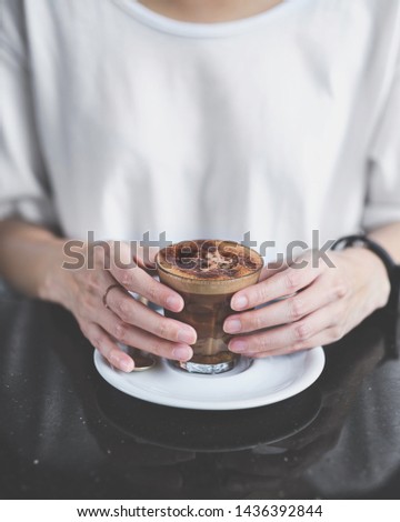 Female hand holding cup of coffee on black marble table.