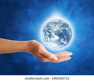 Female hand holding Earth with a shining white halo in the middle of blue starry space. Elements of this image are furnished by NASA