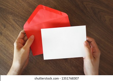 A Female Hand Holding An Envelope And Post Card On Wooden Background 