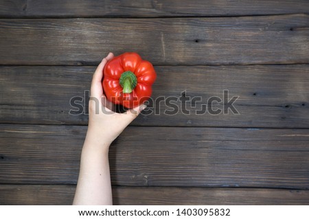 
	
Female hand holding Fresh juicy peppers on a wood background    				