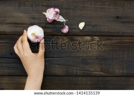             
Female hand holding Garlic on a wood background 
                   