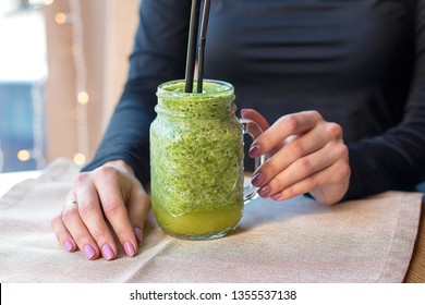 Female hand holding a glass of fresh organic green cocktail with spinach, avocado, banana, Chia on colorful kitchen background. Detox, alkaline diet, weight loss and a healthy lifestyle. - Shutterstock ID 1355537138