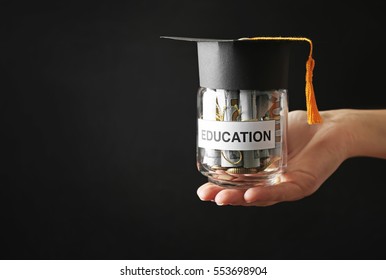 Female Hand Holding Glass Jar With Money For Education, On Dark Background