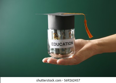 Female Hand Holding Glass Jar With Money For Education, On Green Background