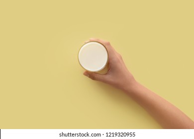 Female Hand Holding Glass Of Milk On Color Background