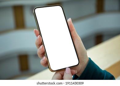 female hand holding golden phone with isolated screen in hotel lobby 