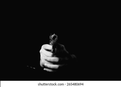 female hand holding gun with a black background 