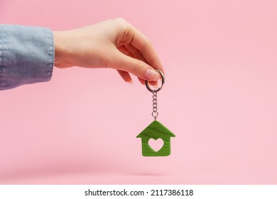 Female hand holding a house keychain. Pink background. Concept of mortgage, leasing of real estate. - Powered by Shutterstock