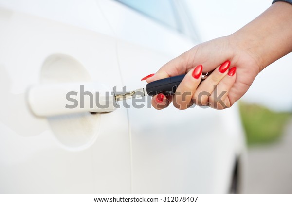 Female hand holding\
key and opening car door