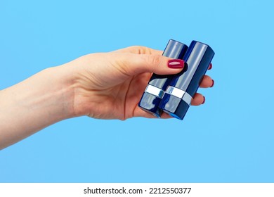 Female hand holding lipstick against blue background