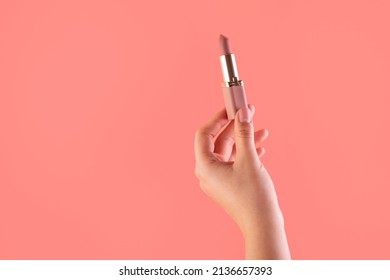 Female hand holding lipstick. Equipment for maquillage. Make-up and visagist. Place for text or creative design. Mockup style. Cosmetic and beauty concept. Isolated on pink