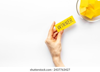 Female hand holding lottery ticket with winner word near glass bowl full of paper sheets. Winner concept. - Powered by Shutterstock